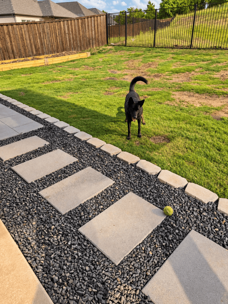 Large concrete pavers set in black river rock with paver block edging next to the lawn