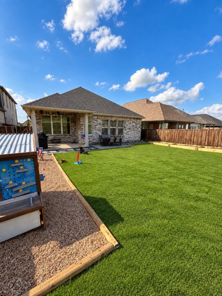 After: backyard with a DIY paver patio and outdoor dining table, rock border, garden beds and a kids' play area